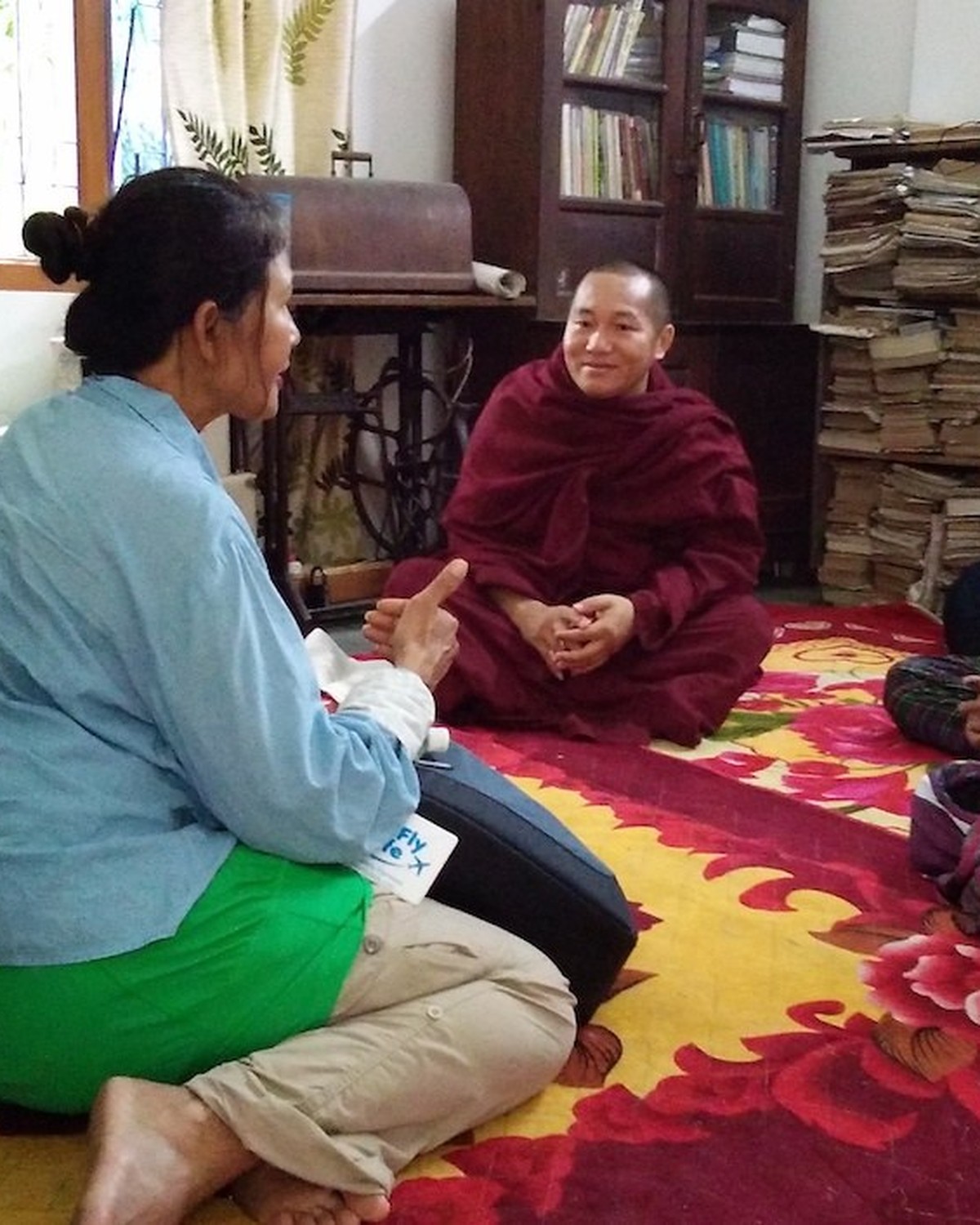 A visitor in conversation with a monk in a monastery library