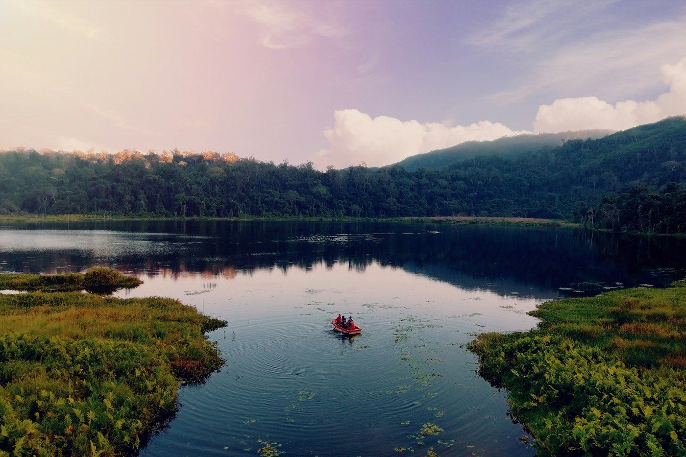 A boat on a still lake among forested hills