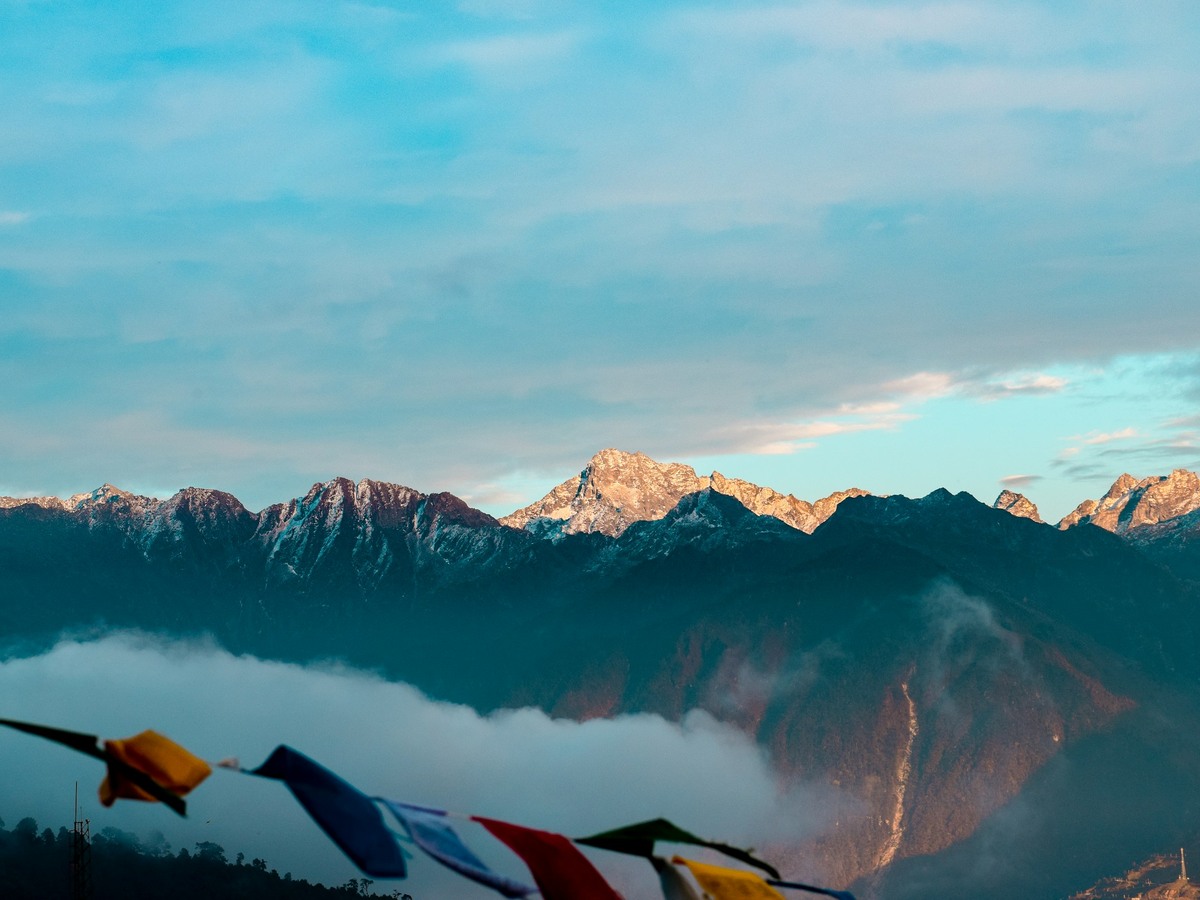 Snow peaks standing above a sea of cloud, prayer flags in front