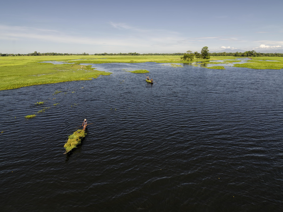 Small boats on a flooded wetland with green grass beyond