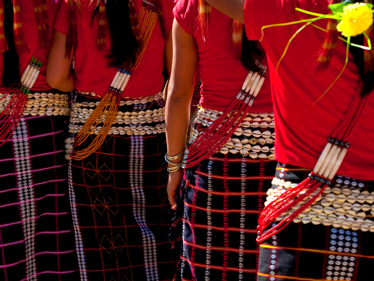 Women in red handwoven skirts and jewelry