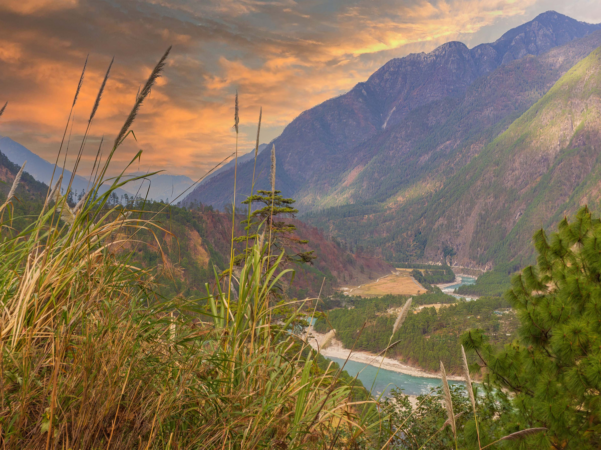 The Lohit river winding through its valley below grassy slopes at sunset