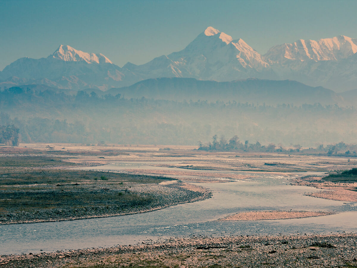 The wide Noa-Dihing riverbed with snow peaks on the horizon