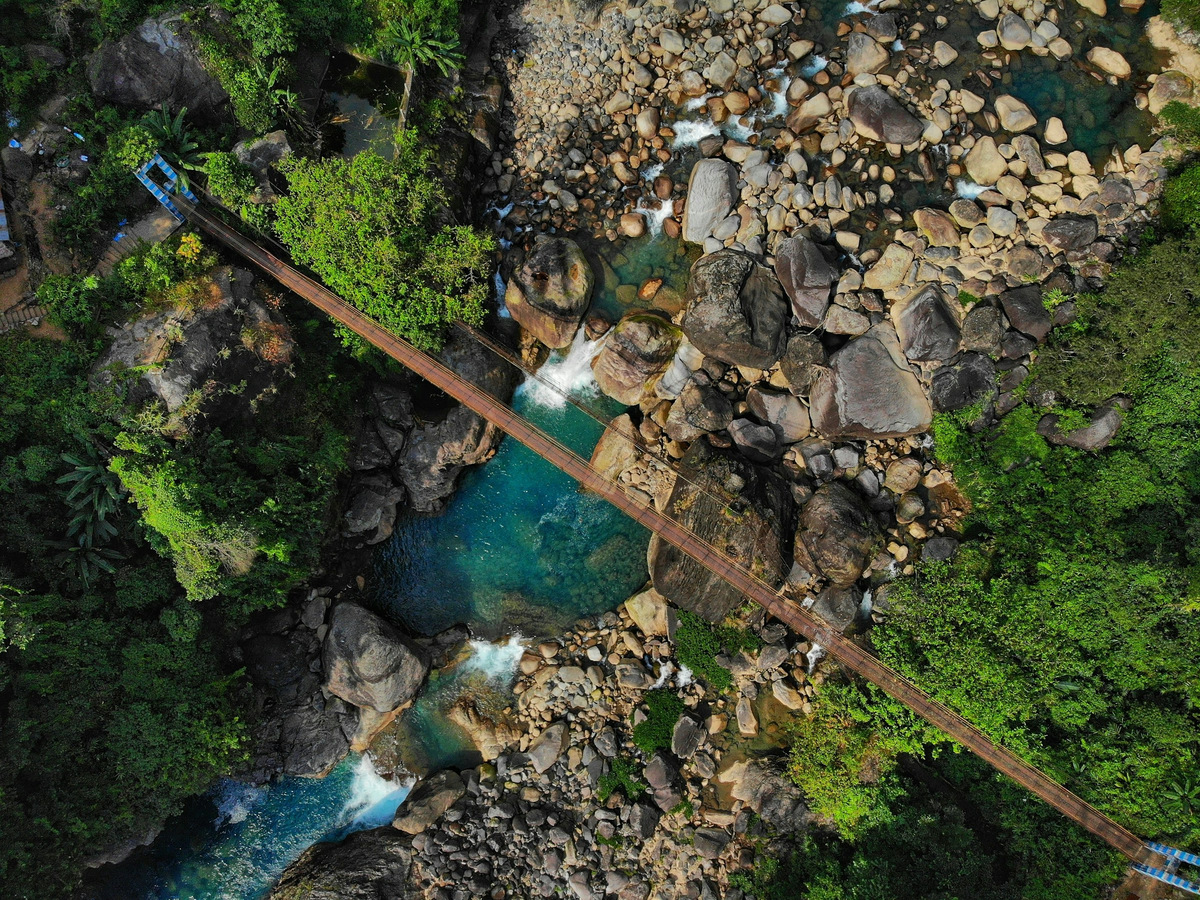 A hanging bridge over a rocky gorge seen from above