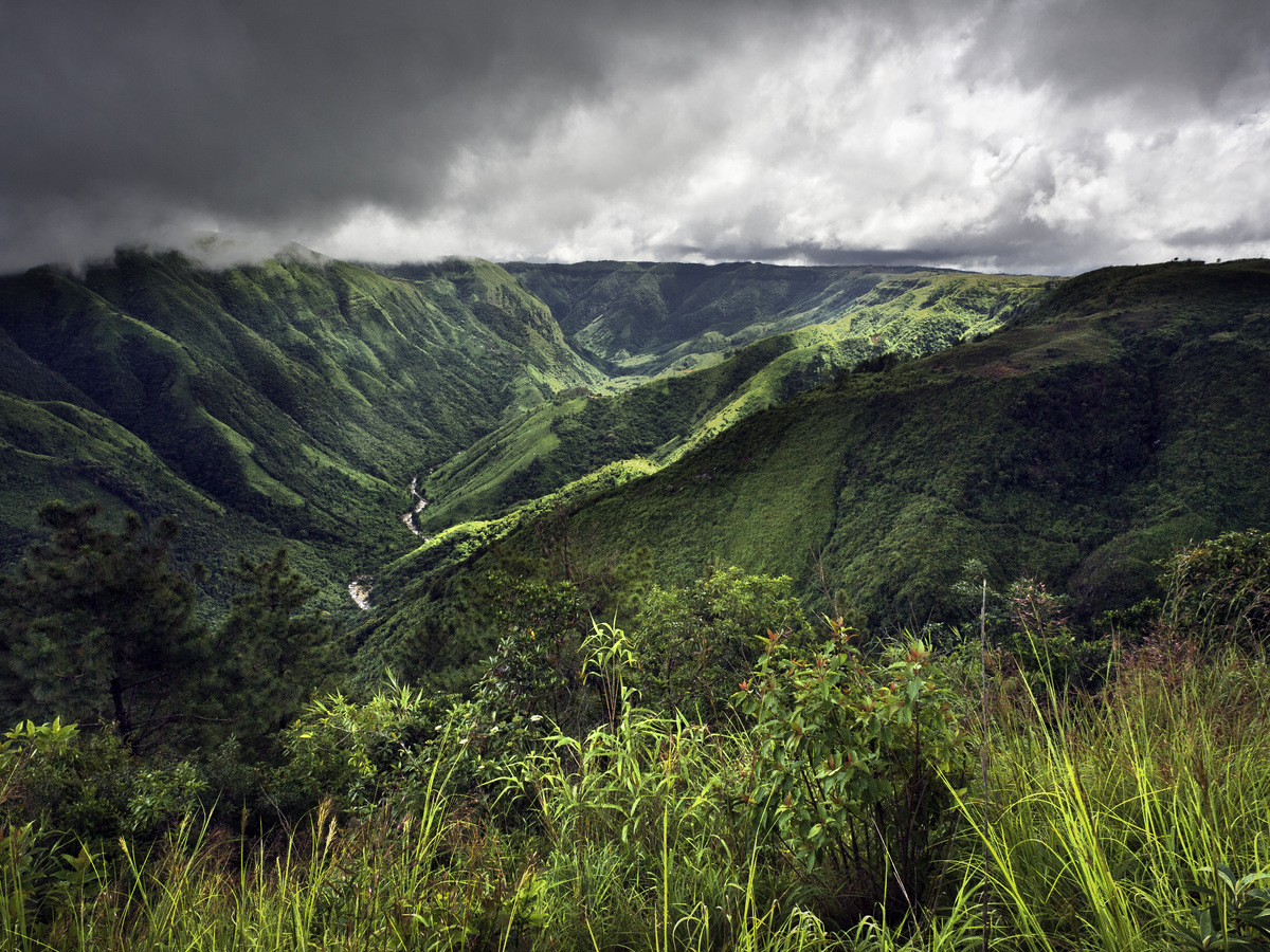 A deep green valley in the Khasi Hills under heavy cloud