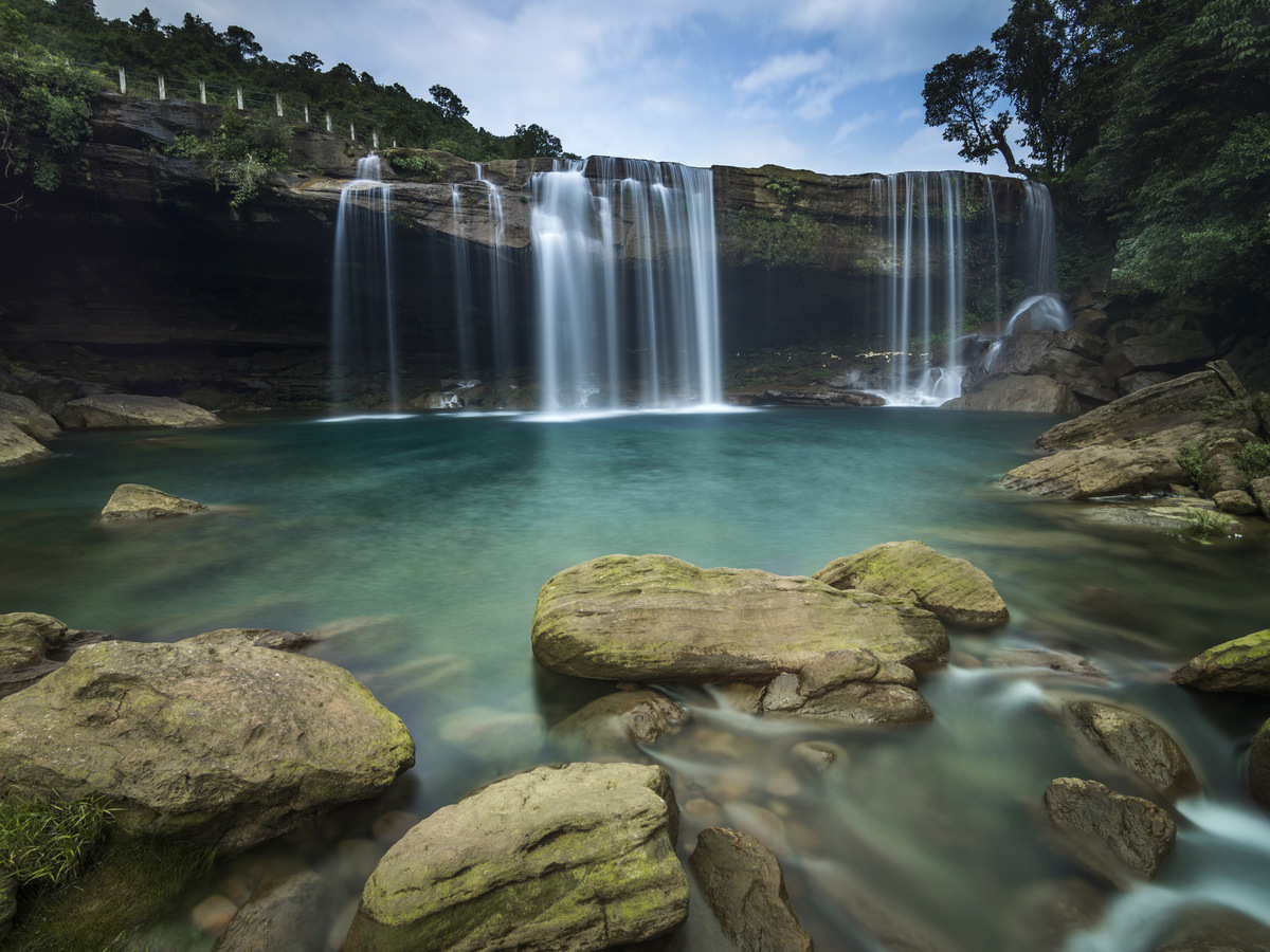A wide waterfall pouring into a clear blue pool