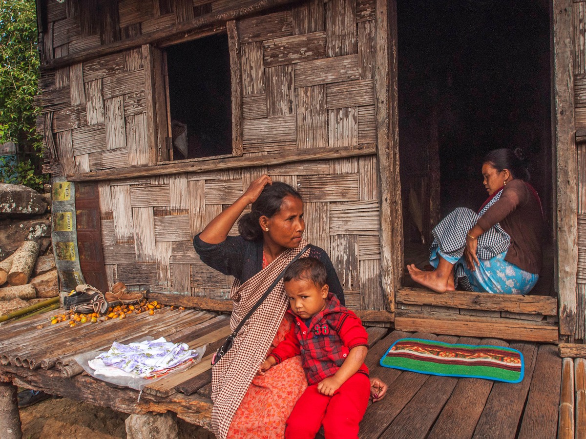 A Khasi family sitting on the porch of their wooden house
