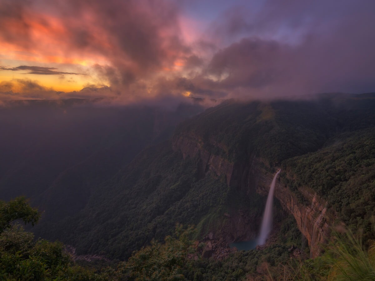 Sunset over a deep gorge with a waterfall on the far wall