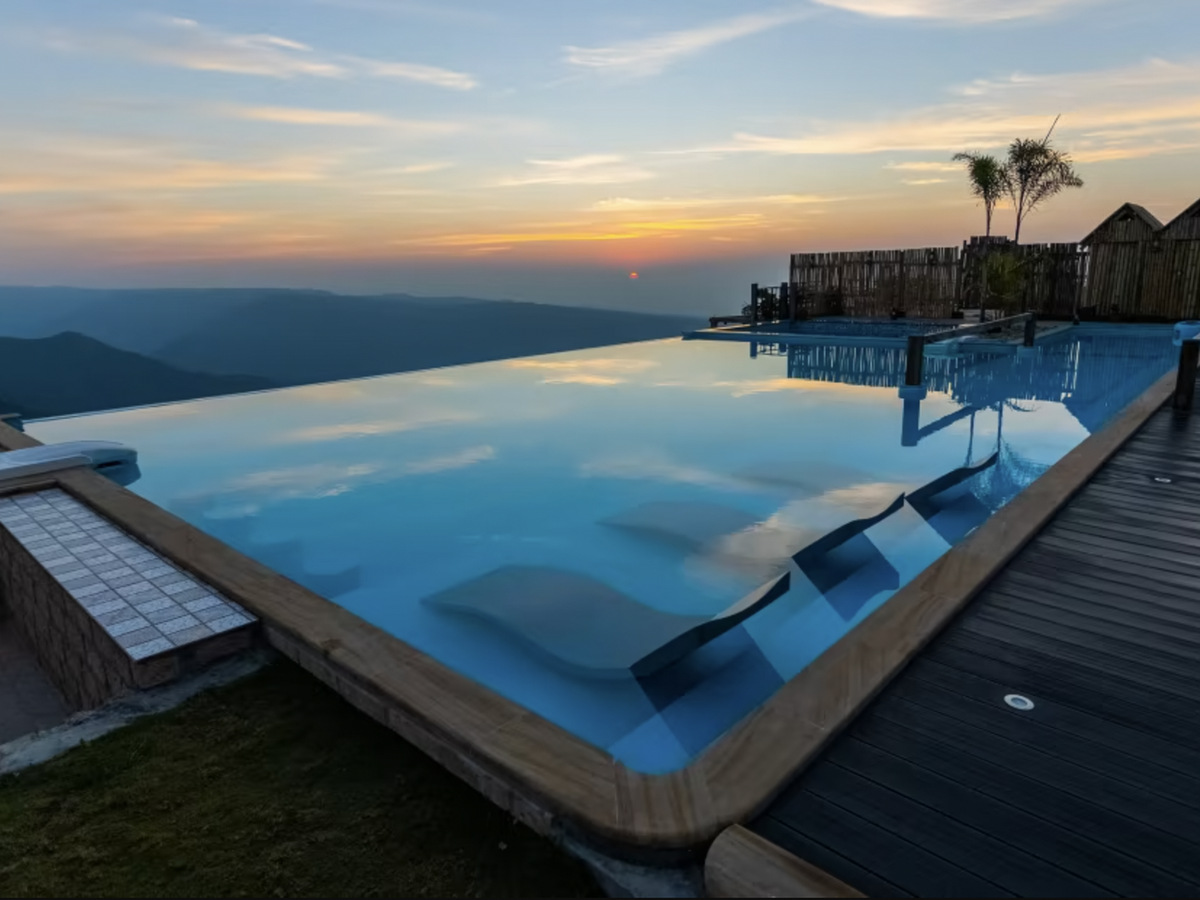 An infinity pool on a cliff edge at sunset, looking over the hills