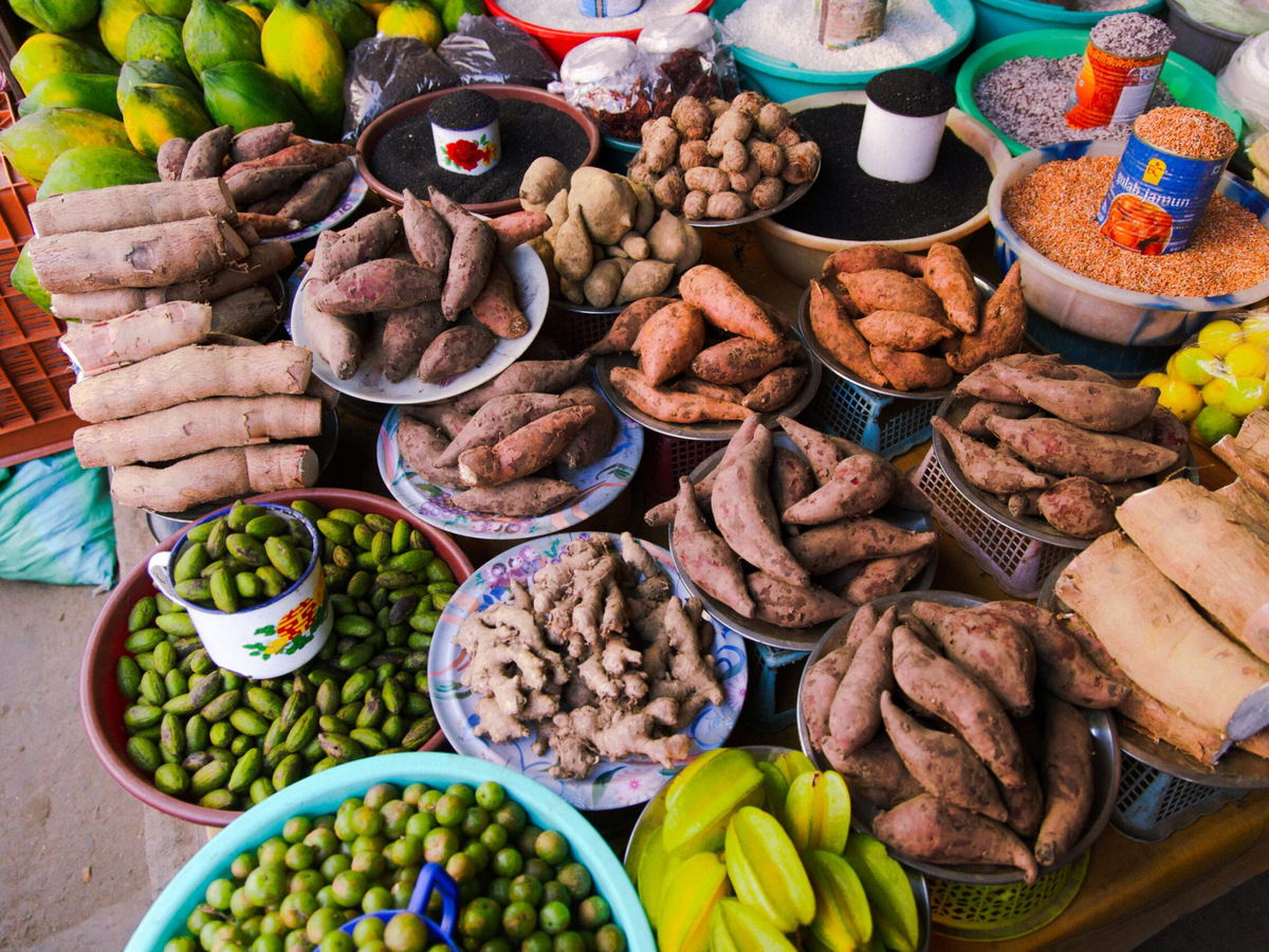 Sweet potatoes, yams, ginger, star fruit and limes laid out at a market stall