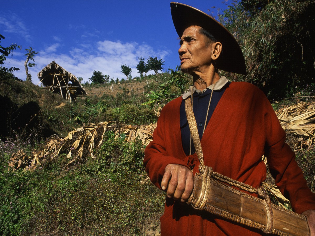 A man in a woven cane hat carrying a cane basket in his fields