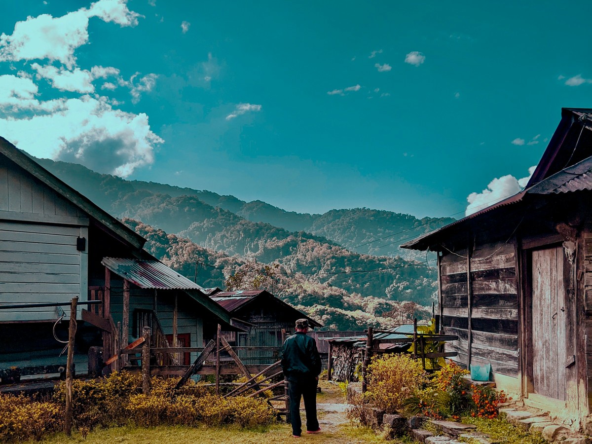 A Konyak village of wooden houses in the morning, a man walking the path between them