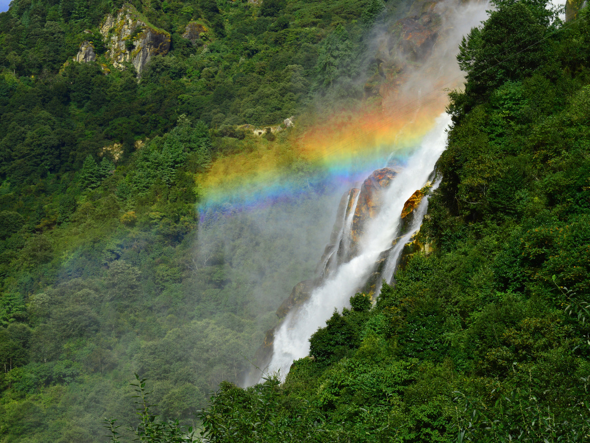 A tall waterfall with a rainbow in its spray